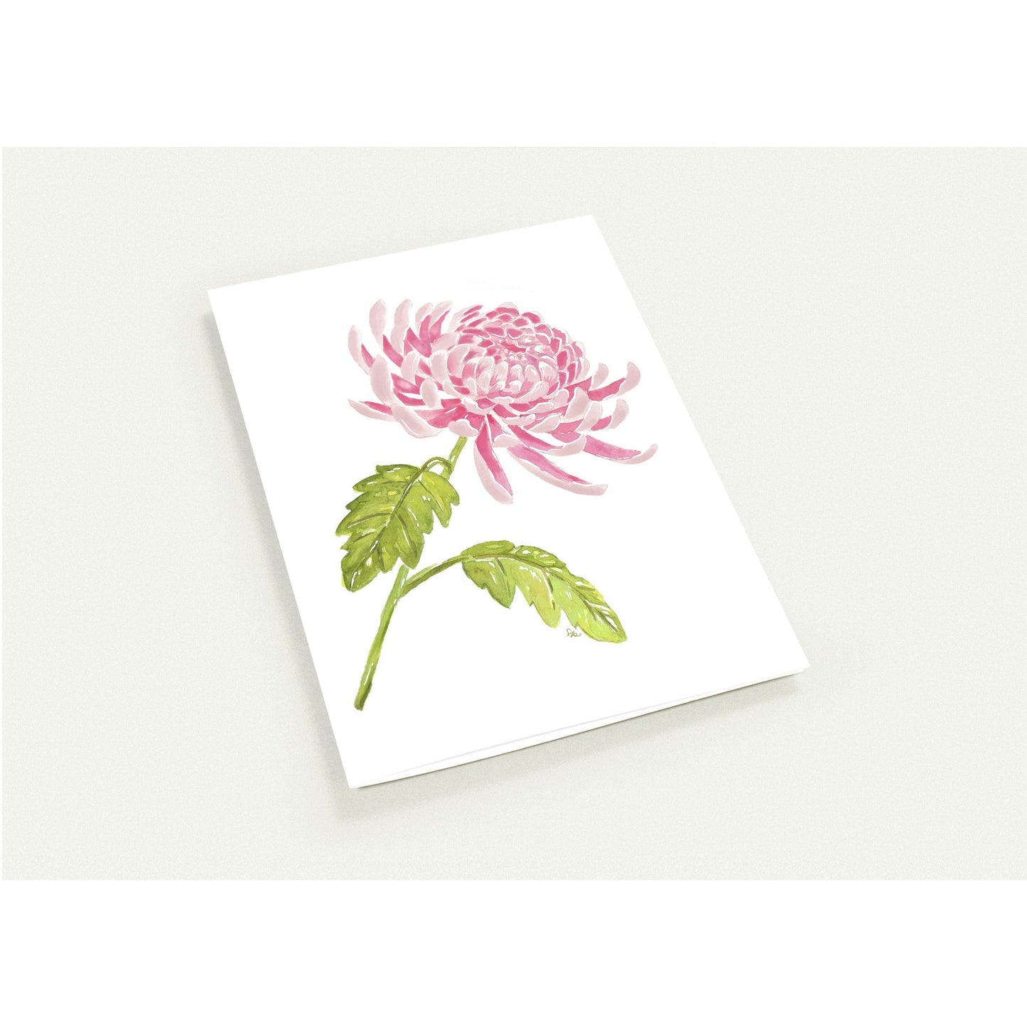 A white greeting card featuring a watercolor illustration of a pink chrysanthemum flower with green leaves, shown on a light gray background.