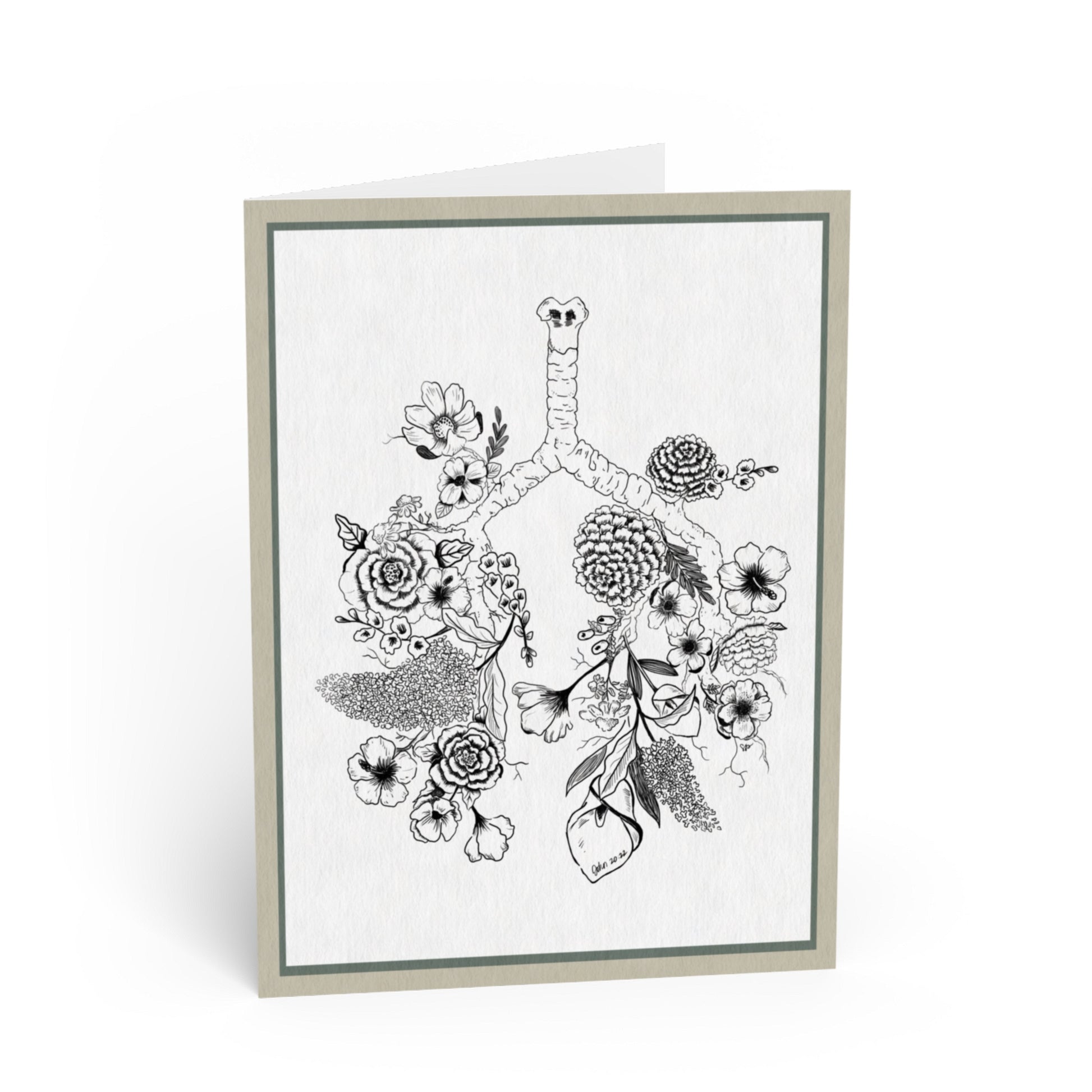 A folded greeting card standing upright, featuring a black-and-white botanical illustration of lungs surrounded by flowers and leaves. The card has a light gray border and is photographed on a clean white background.