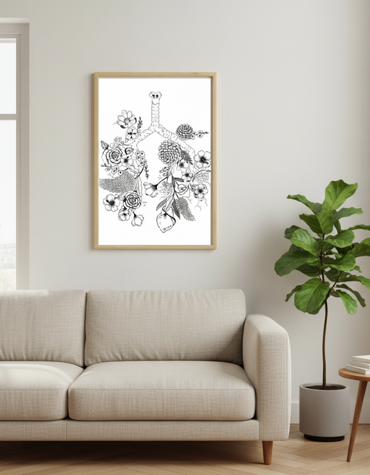 Living room with a beige sofa, framed artwork of flowers coming out of lungs on the wall, and a potted plant.