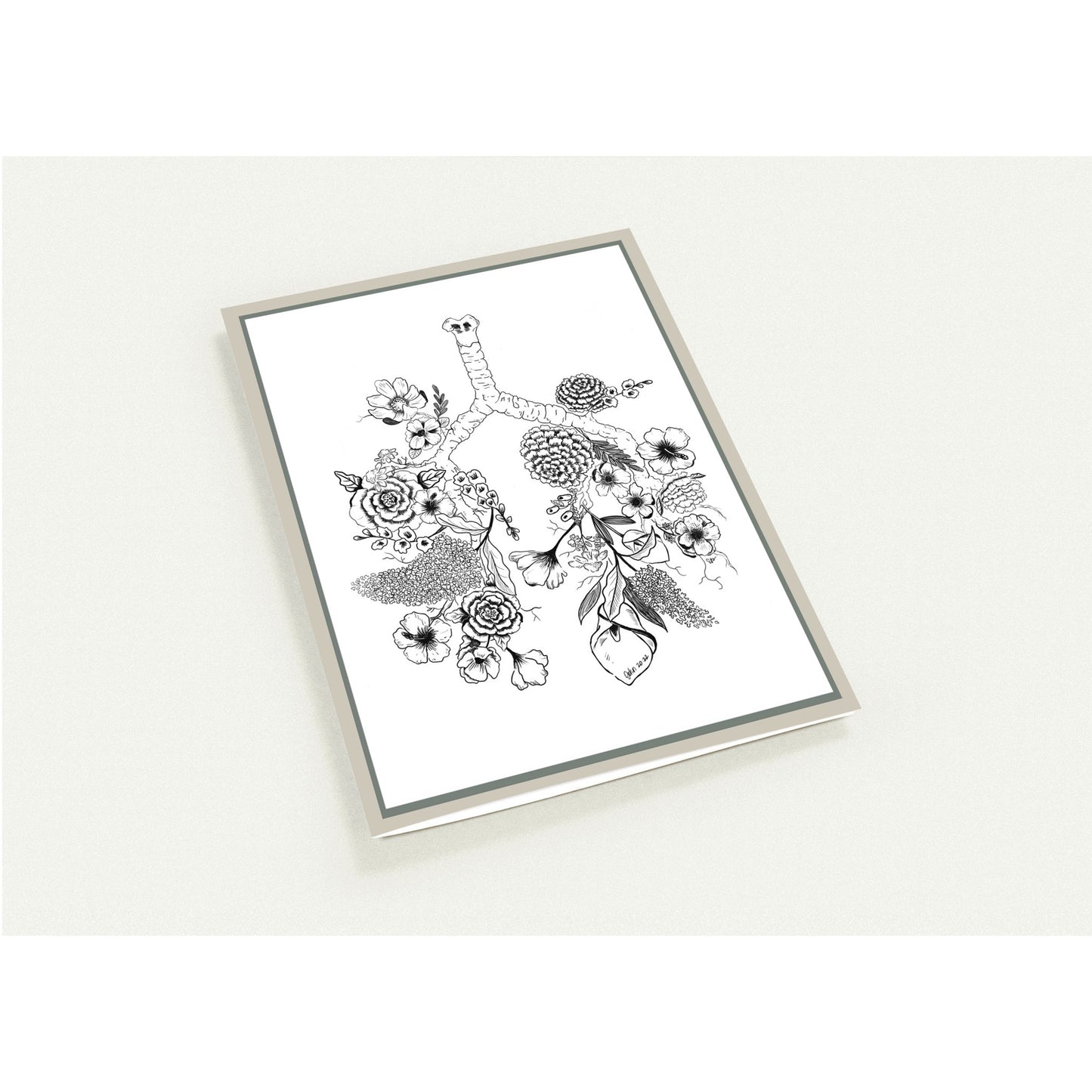 A framed botanical art card featuring black ink illustrations of flowers and leaves on a white background, enclosed in a thin silver frame and photographed against a light neutral backdrop.